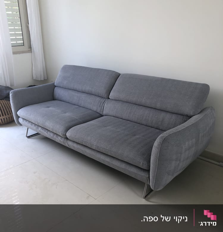 ספה אפורה על רצפה בהירה ליד חלון